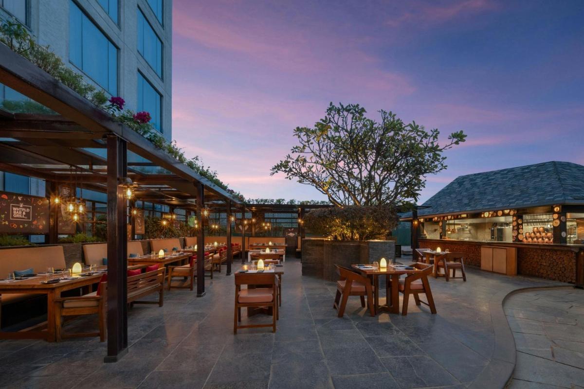 an outdoor patio with tables and chairs and a building at Bengaluru Marriott Hotel Whitefield in Bengaluru