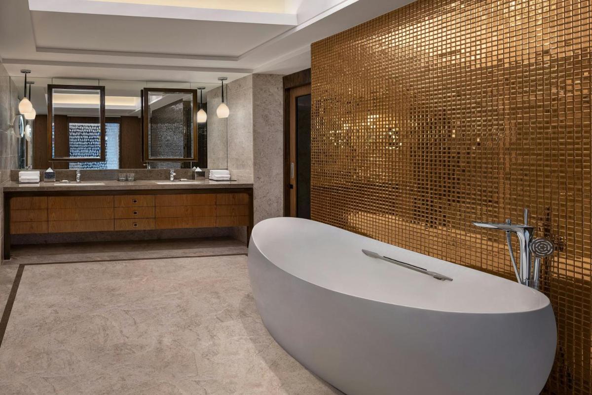 a bathroom with a tub and two sinks and a mirror at Bengaluru Marriott Hotel Whitefield in Bengaluru