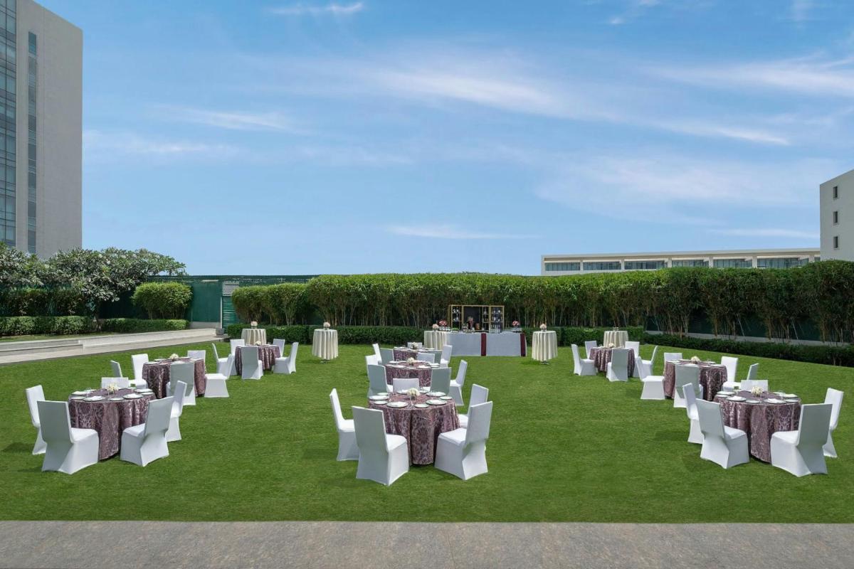 a group of tables and chairs on a field of grass at Bengaluru Marriott Hotel Whitefield in Bengaluru