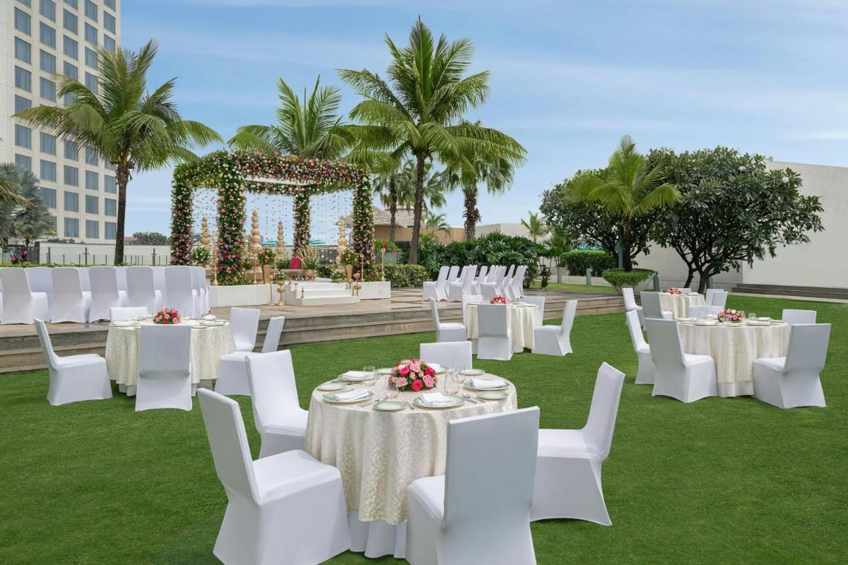 a wedding reception with white tables and white chairs at Bengaluru Marriott Hotel Whitefield in Bengaluru