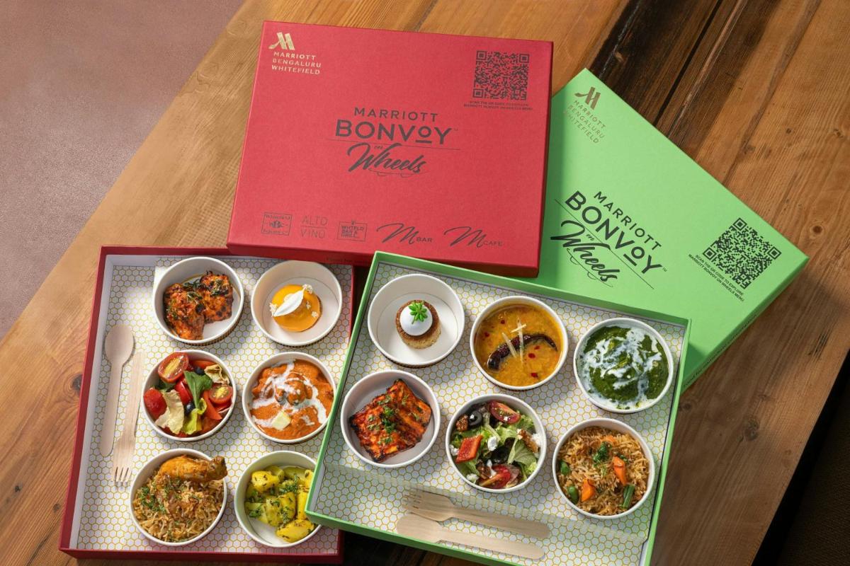 a box with various dishes of food on a table at Bengaluru Marriott Hotel Whitefield in Bengaluru