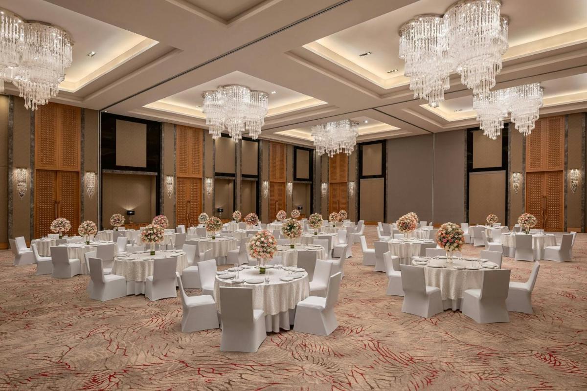 a ballroom with white tables and chairs and chandeliers at Bengaluru Marriott Hotel Whitefield in Bengaluru