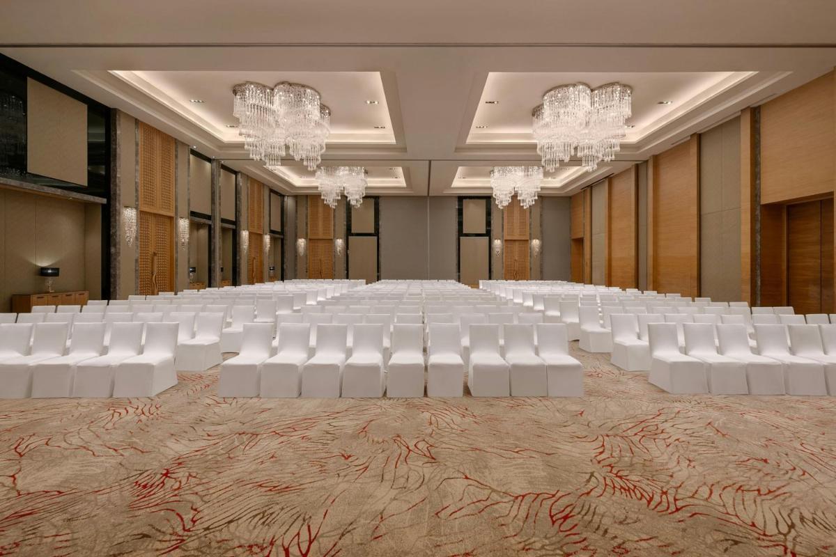a large banquet hall with white chairs and chandeliers at Bengaluru Marriott Hotel Whitefield in Bengaluru