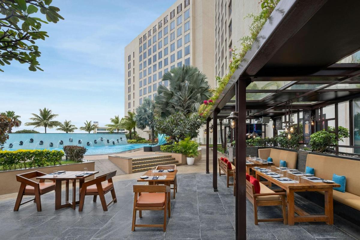 an outdoor patio with tables and chairs and a pool at Bengaluru Marriott Hotel Whitefield in Bengaluru