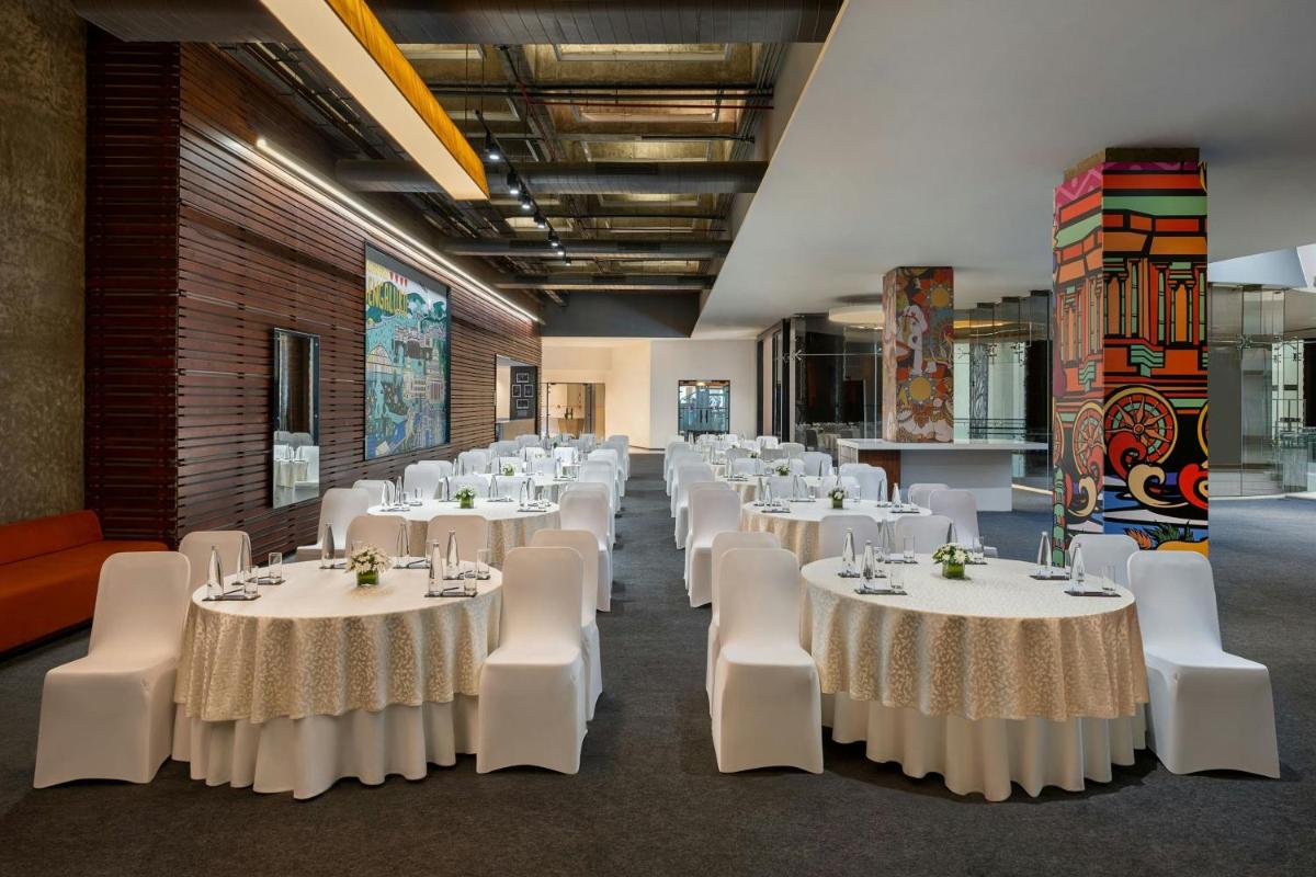 a banquet hall with white tables and white chairs at Bengaluru Marriott Hotel Whitefield in Bengaluru