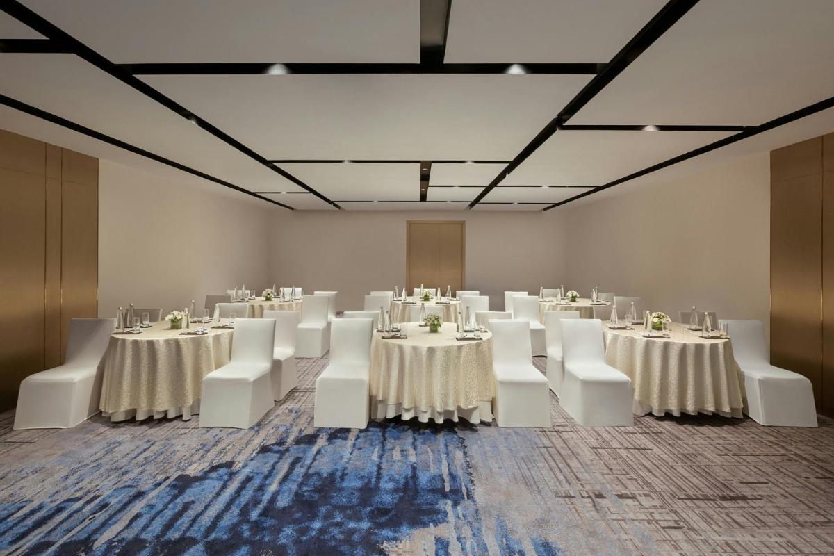 a large room with white tables and white chairs at Bengaluru Marriott Hotel Whitefield in Bengaluru