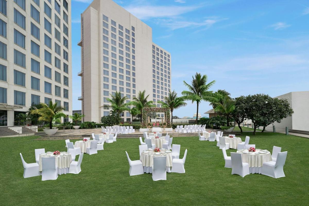 a group of tables and chairs in a field with buildings at Bengaluru Marriott Hotel Whitefield in Bengaluru