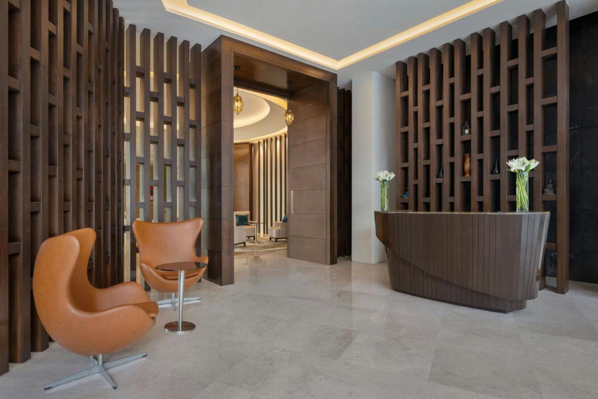 a lobby with two chairs and a reception desk at Bengaluru Marriott Hotel Whitefield in Bengaluru