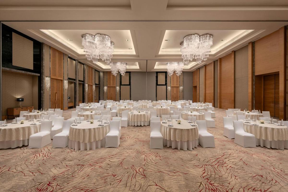 a ballroom with white tables and chairs and chandeliers at Bengaluru Marriott Hotel Whitefield in Bengaluru