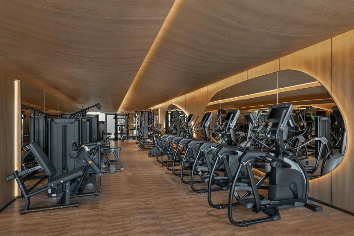 a gym with a row of tread machines at Bengaluru Marriott Hotel Whitefield in Bengaluru