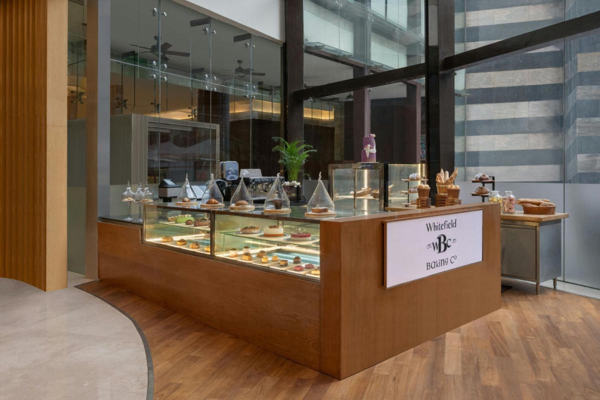 a display case with many different types of desserts at Bengaluru Marriott Hotel Whitefield in Bengaluru