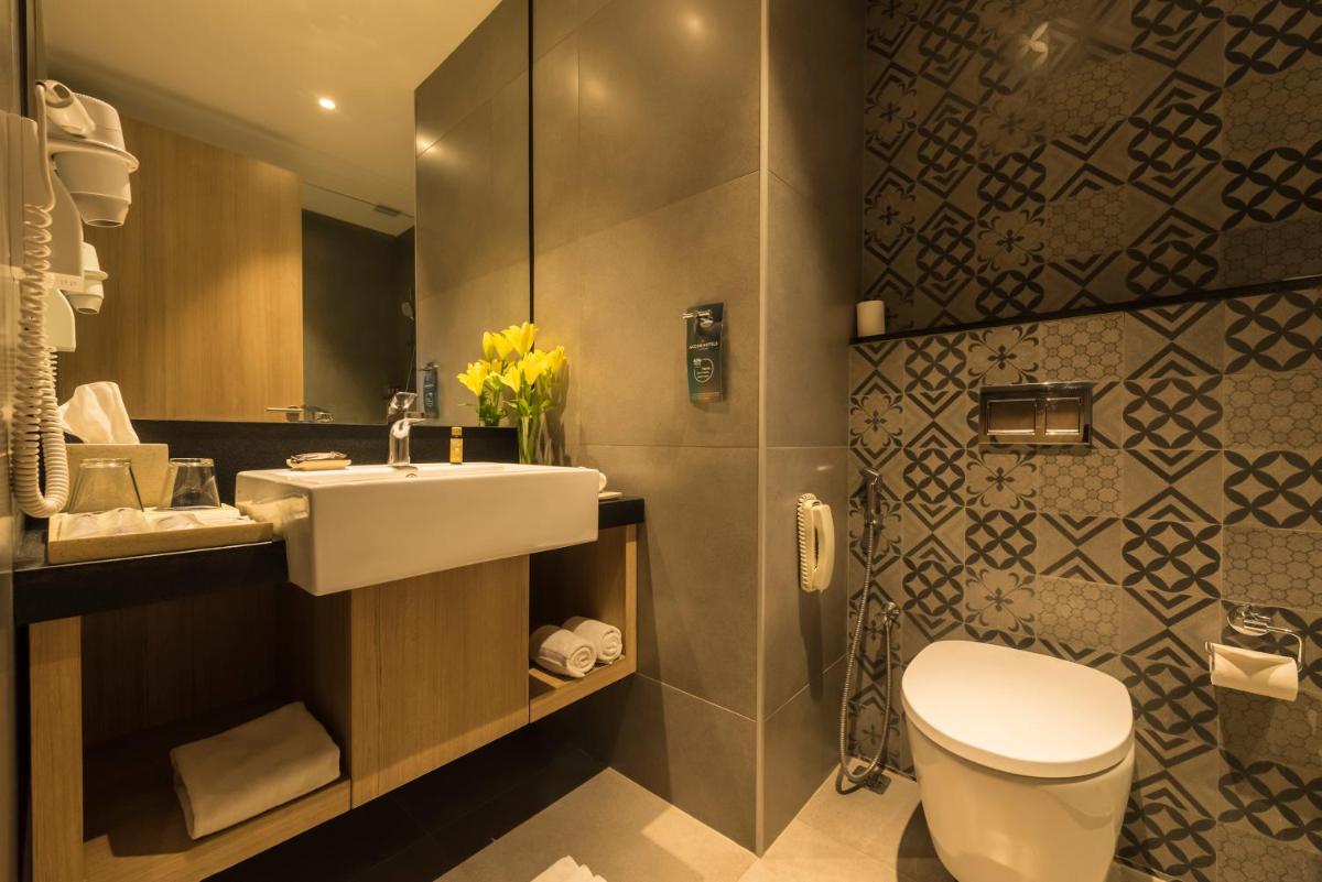 a bathroom with a sink and a toilet and a mirror at Grand Mercure Mysore - An Accor Brand in Mysore