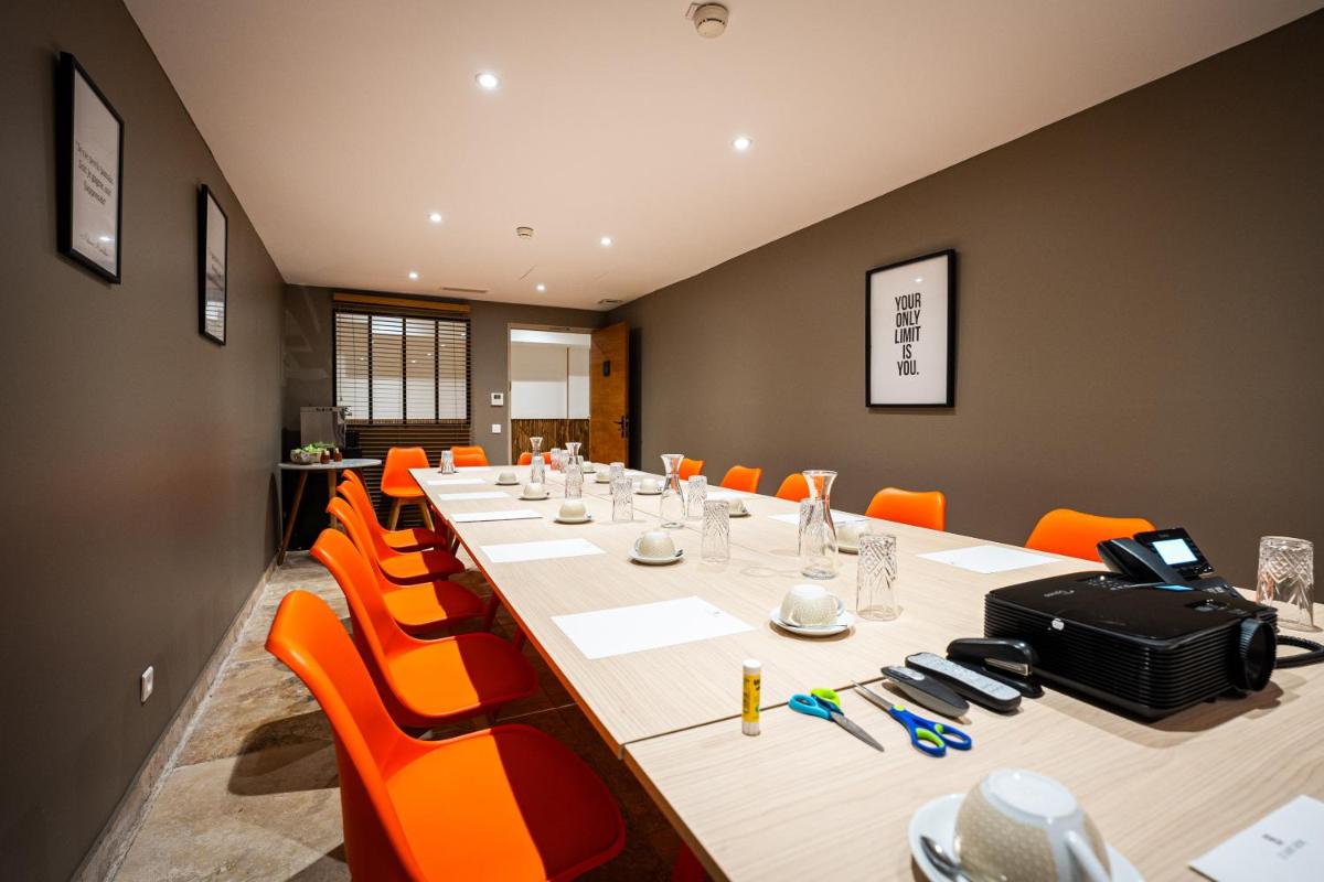une salle de conférence avec une longue table et des chaises orange dans l'établissement Hôtel Le Saint Remy & Spa, à Saint-Rémy-de-Provence 104 autres photos