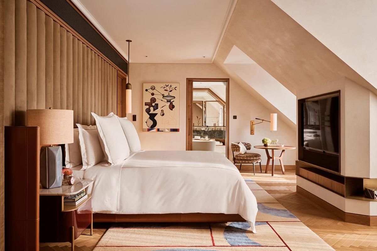 ein Schlafzimmer mit einem großen weißen Bett und einem Fernseher in der Unterkunft Rosewood Munich in München + 100 Fotos