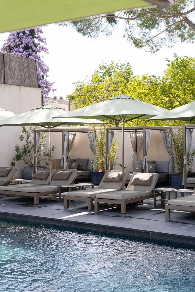 un groupe de chaises longues et de parasols à côté d'une piscine dans l'établissement Hôtel Le Saint Remy & Spa, à Saint-Rémy-de-Provence