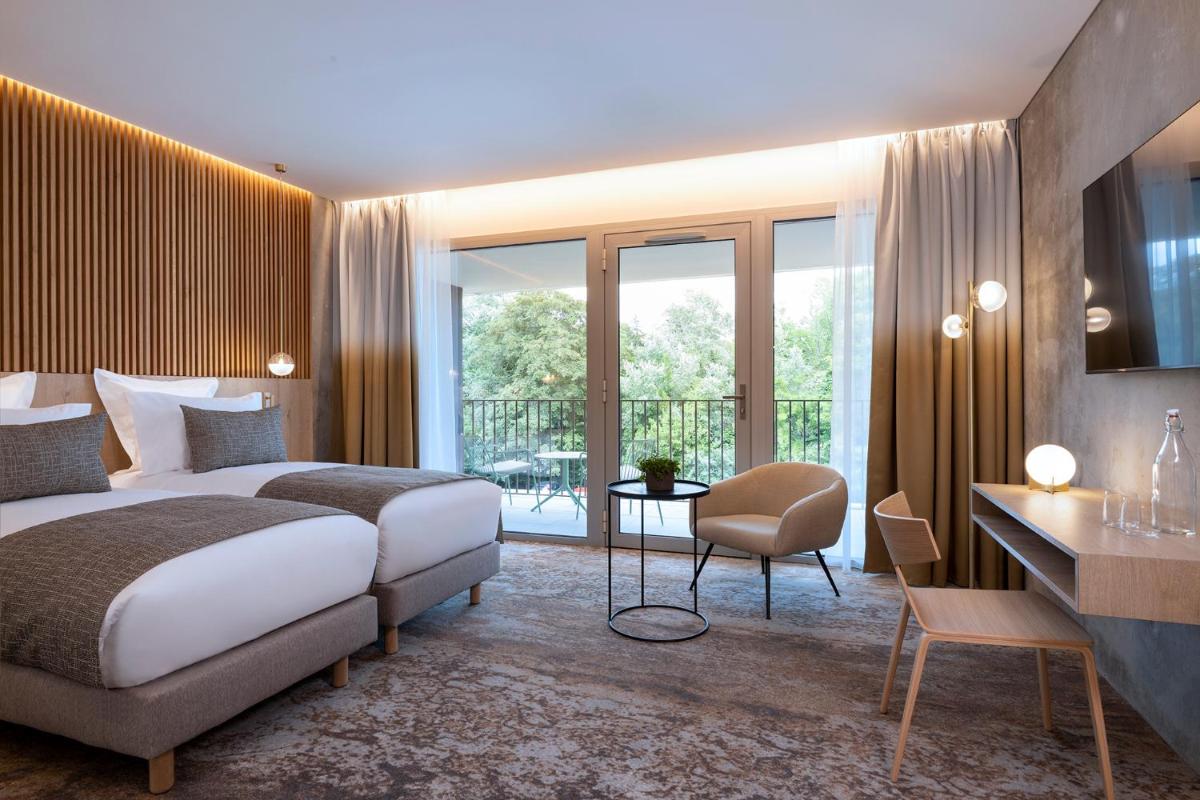 une chambre d'hôtel avec un grand lit et un bureau et un bureau dans l'établissement Hôtel Spa Restaurant Villa Castellane, à Gréoux-les-Bains