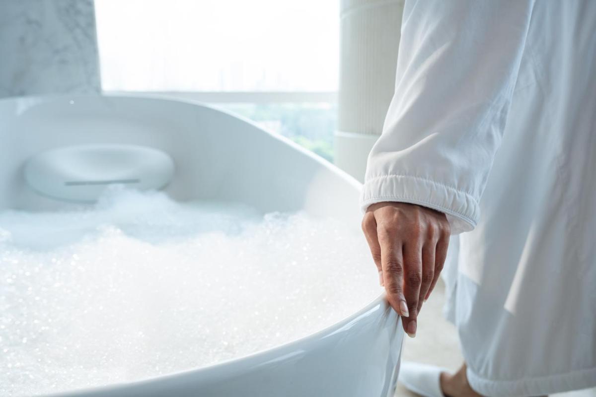 a person standing in a bath tub with his hand on it at Four Seasons Hotel Mumbai in Mumbai