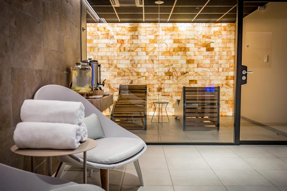 une pièce avec une chaise blanche et un mur de briques dans l'établissement Grand Hôtel du Luxembourg & Spa, à Bayeux