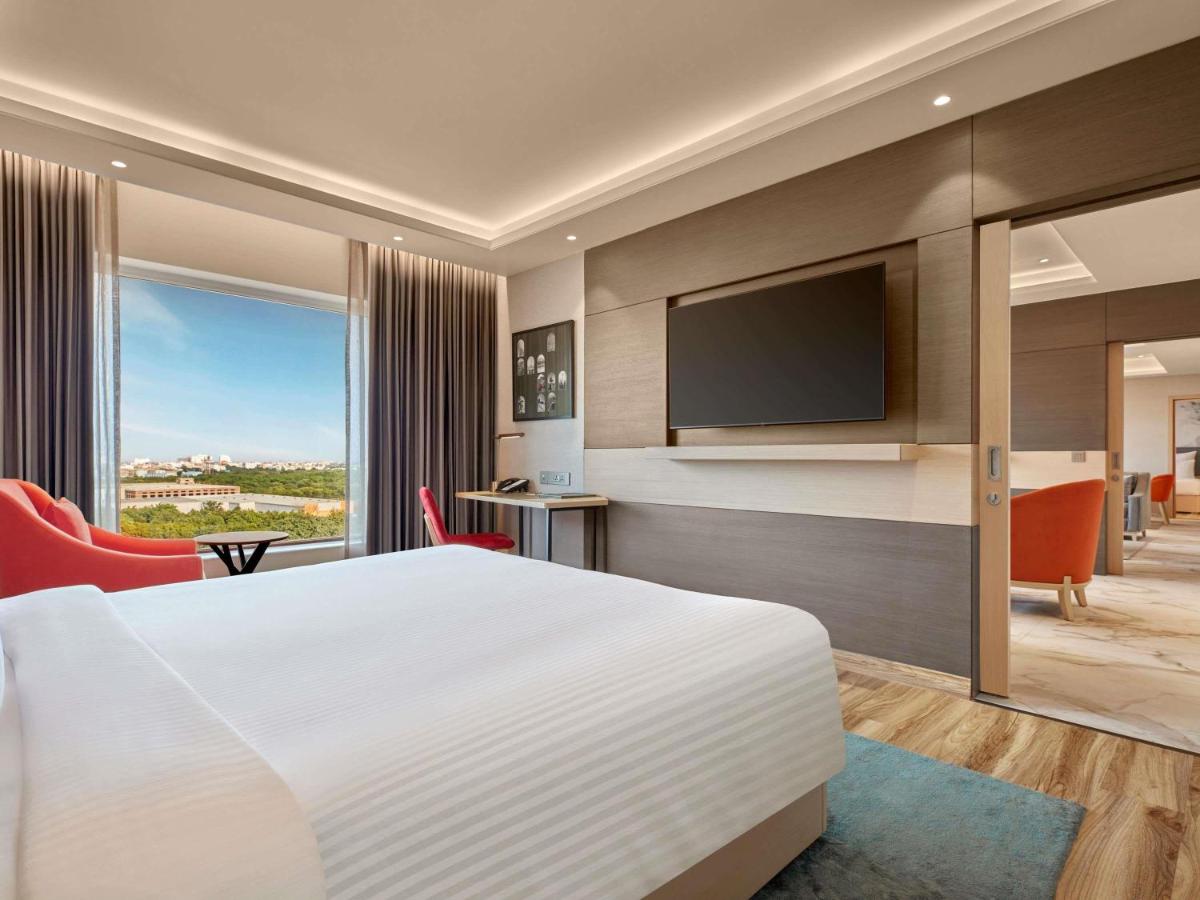 a hotel room with a bed and a flat screen tv at Novotel Jaipur Convention Centre in Jaipur +117 photos