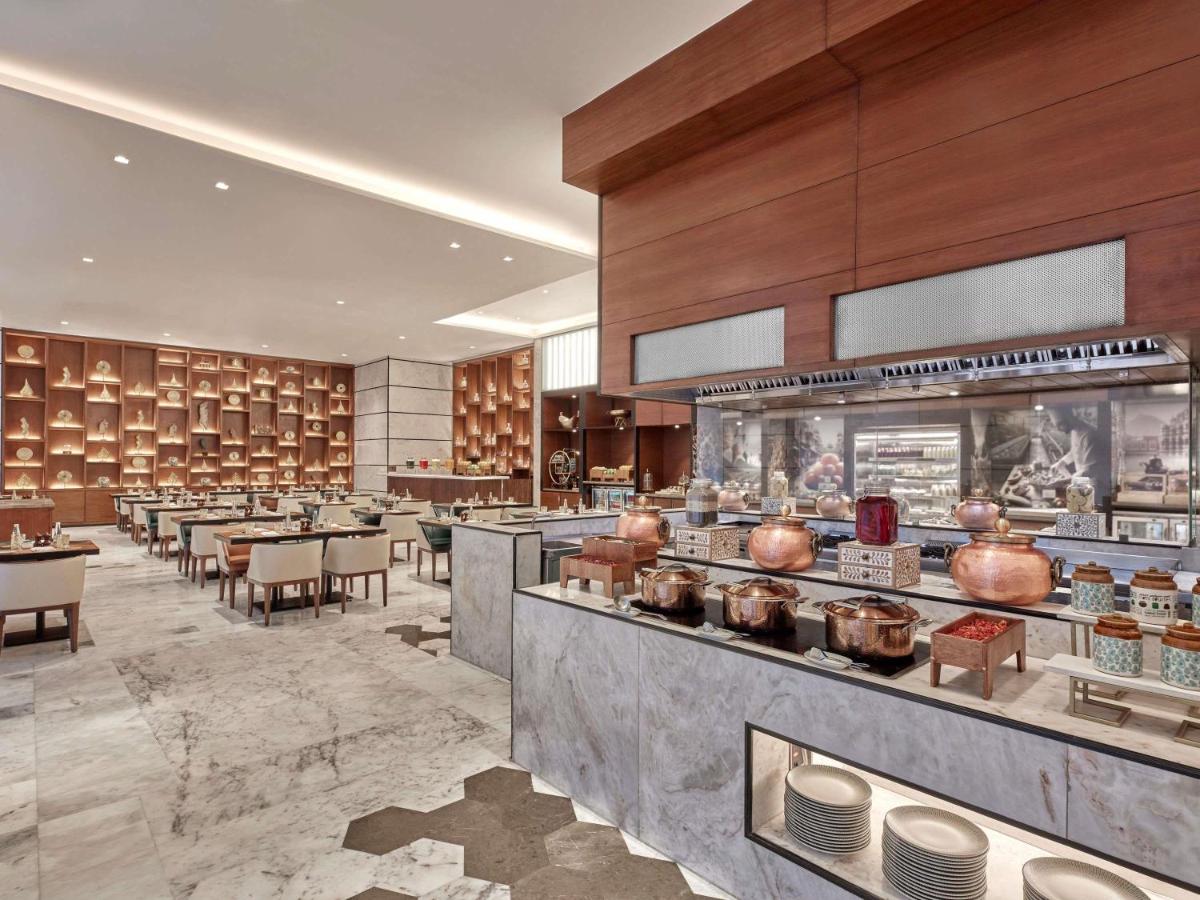 a restaurant with tables and chairs and a buffet at Novotel Jaipur Convention Centre in Jaipur