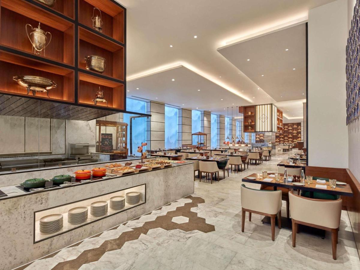 a restaurant with tables and chairs in a building at Novotel Jaipur Convention Centre in Jaipur