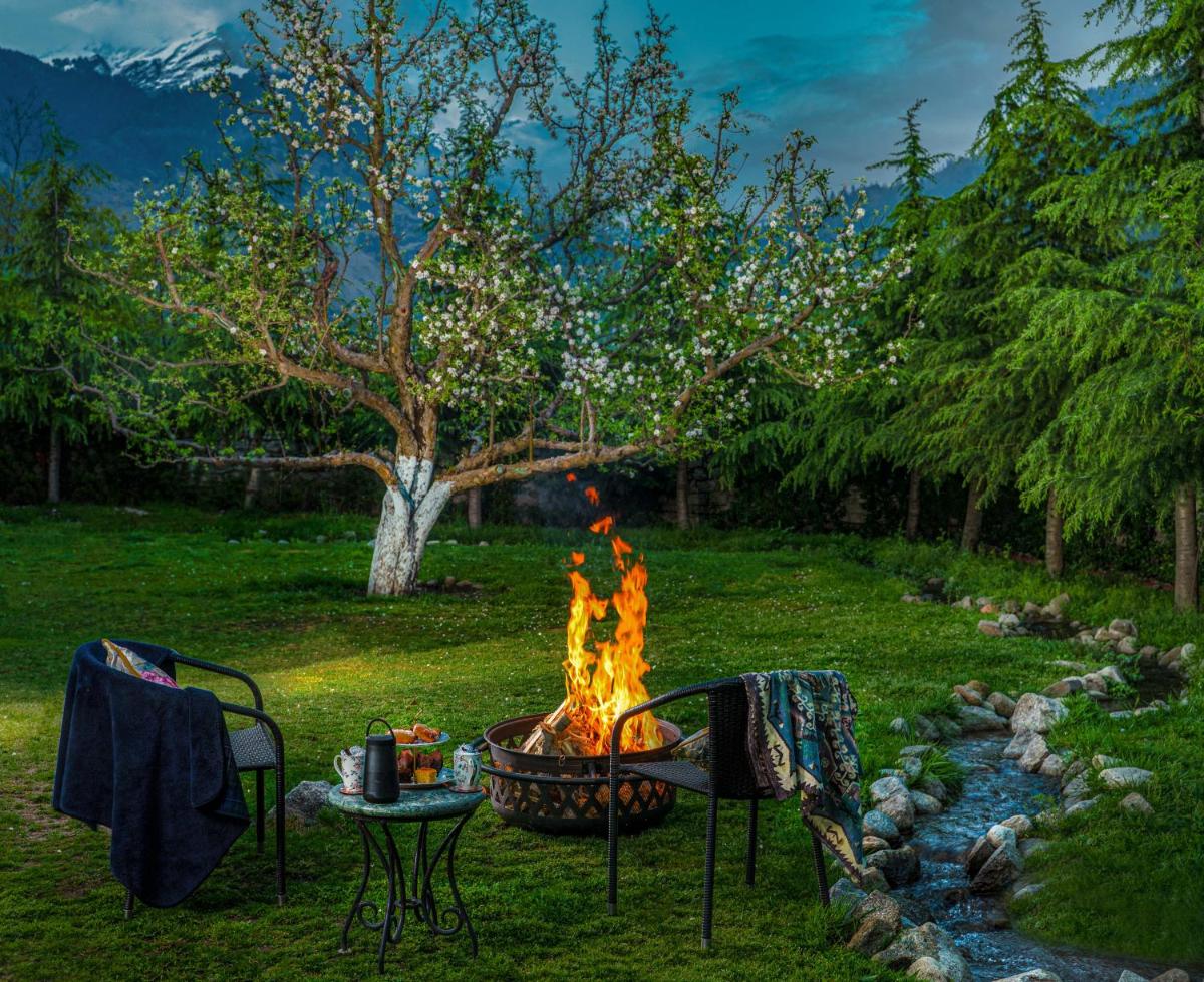 a fire pit in a yard with a table and chairs at Storii By ITC Hotels Urvashis Retreat, Manali in Manāli