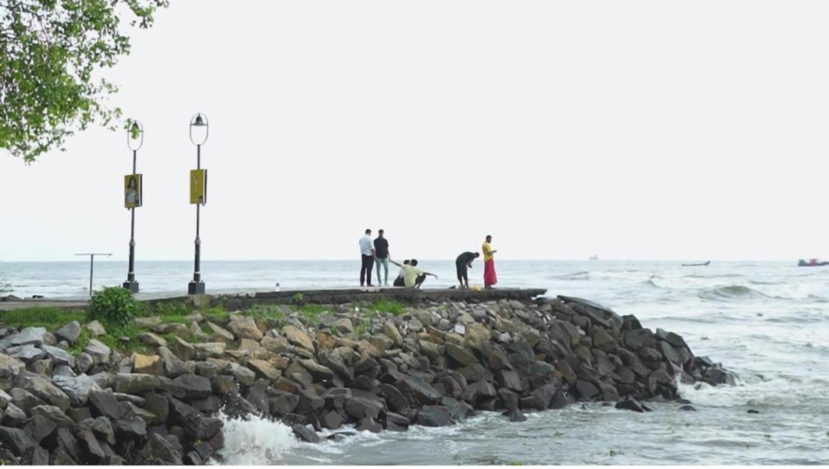 a group of people standing on a rock wall near the water at Radisson Blu Kochi in Cochin