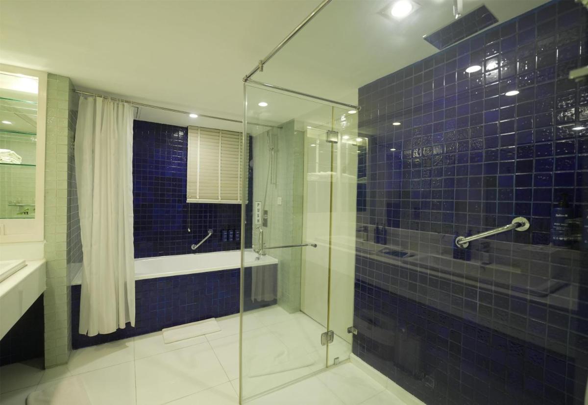 a glass shower in a bathroom with blue tiles at Radisson Blu Kochi in Cochin