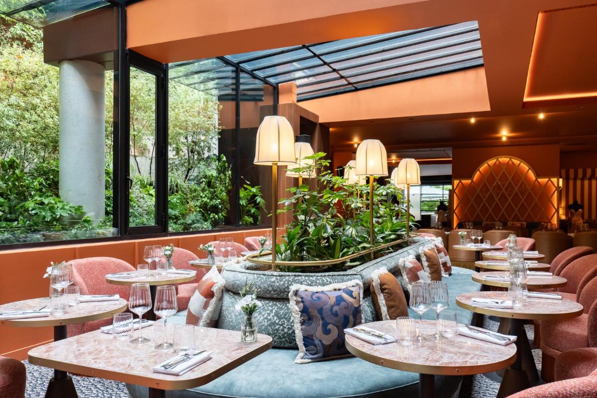 un restaurant avec des tables, des chaises et des fenêtres dans l'établissement La Maison Champs Elysées, à Paris