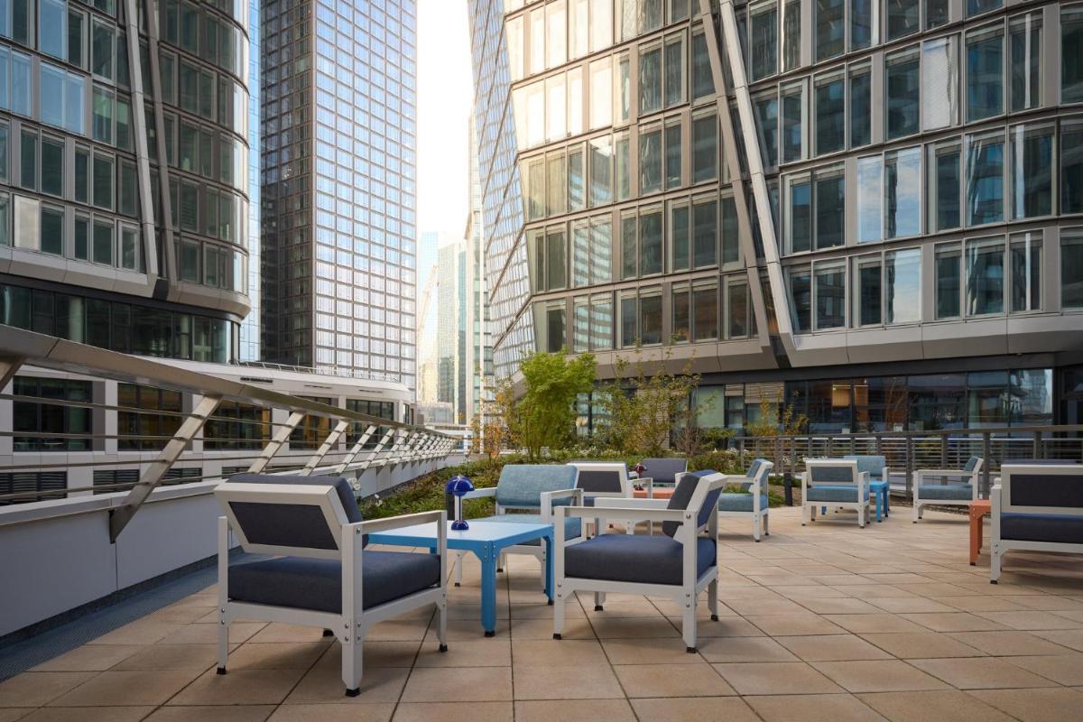 eine Terrasse mit Stühlen und Tischen und hohe Gebäude in der Unterkunft Kimpton Main Frankfurt by IHG in Frankfurt am Main