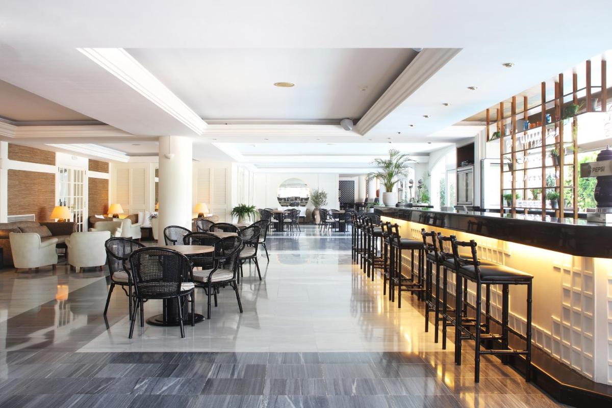 Un restaurante con mesas y sillas y un bar. en Augusta Club & Spa - Adults Only, en Lloret de Mar