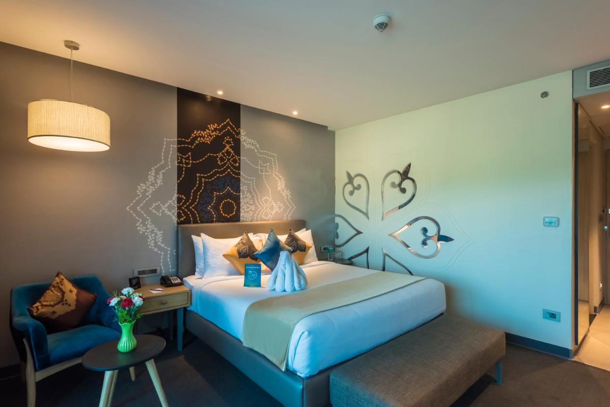 a hotel room with a bed and a chair at Grand Mercure Mysore - An Accor Brand in Mysore