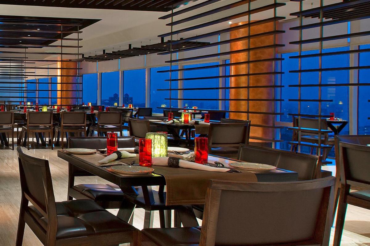 a dining room with tables and chairs and windows at The Westin Mumbai Garden City in Mumbai