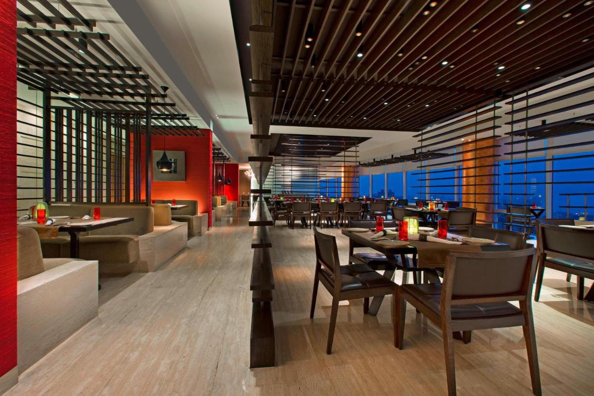 a dining room with tables and chairs in a restaurant at The Westin Mumbai Garden City in Mumbai
