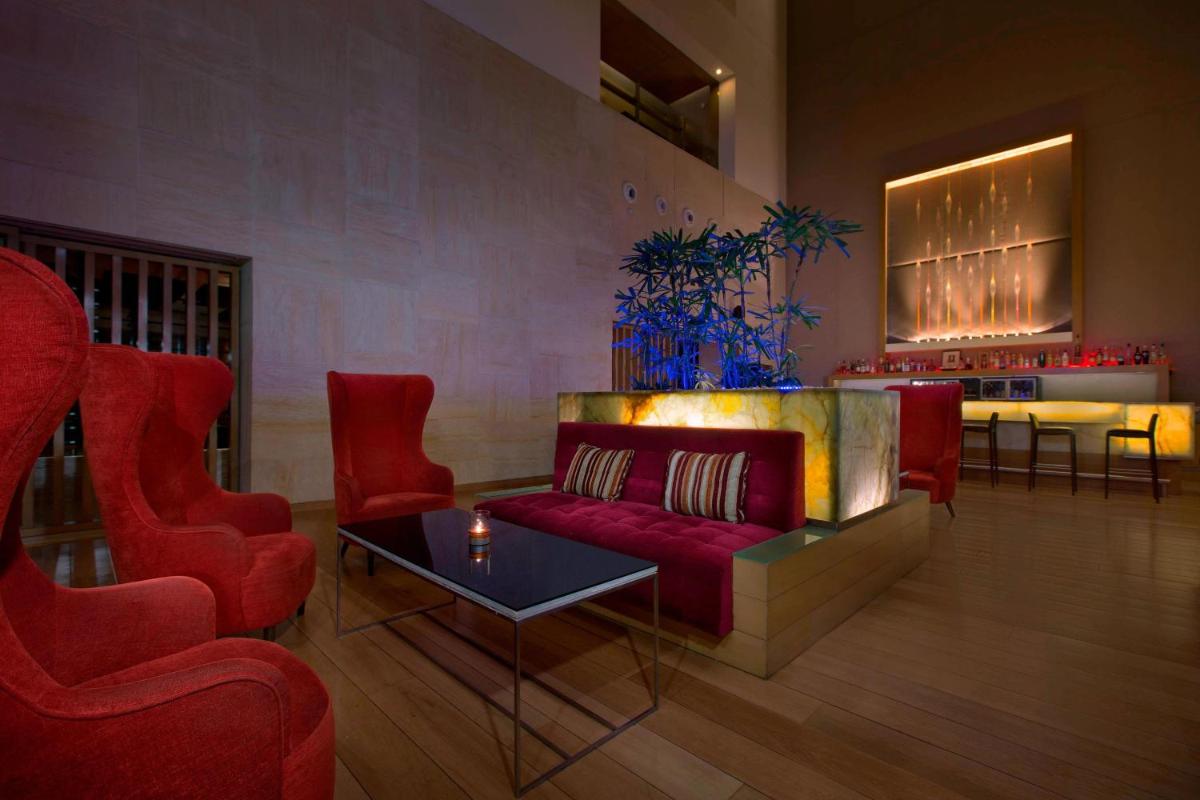 a living room with a red couch and two chairs at The Westin Mumbai Garden City in Mumbai