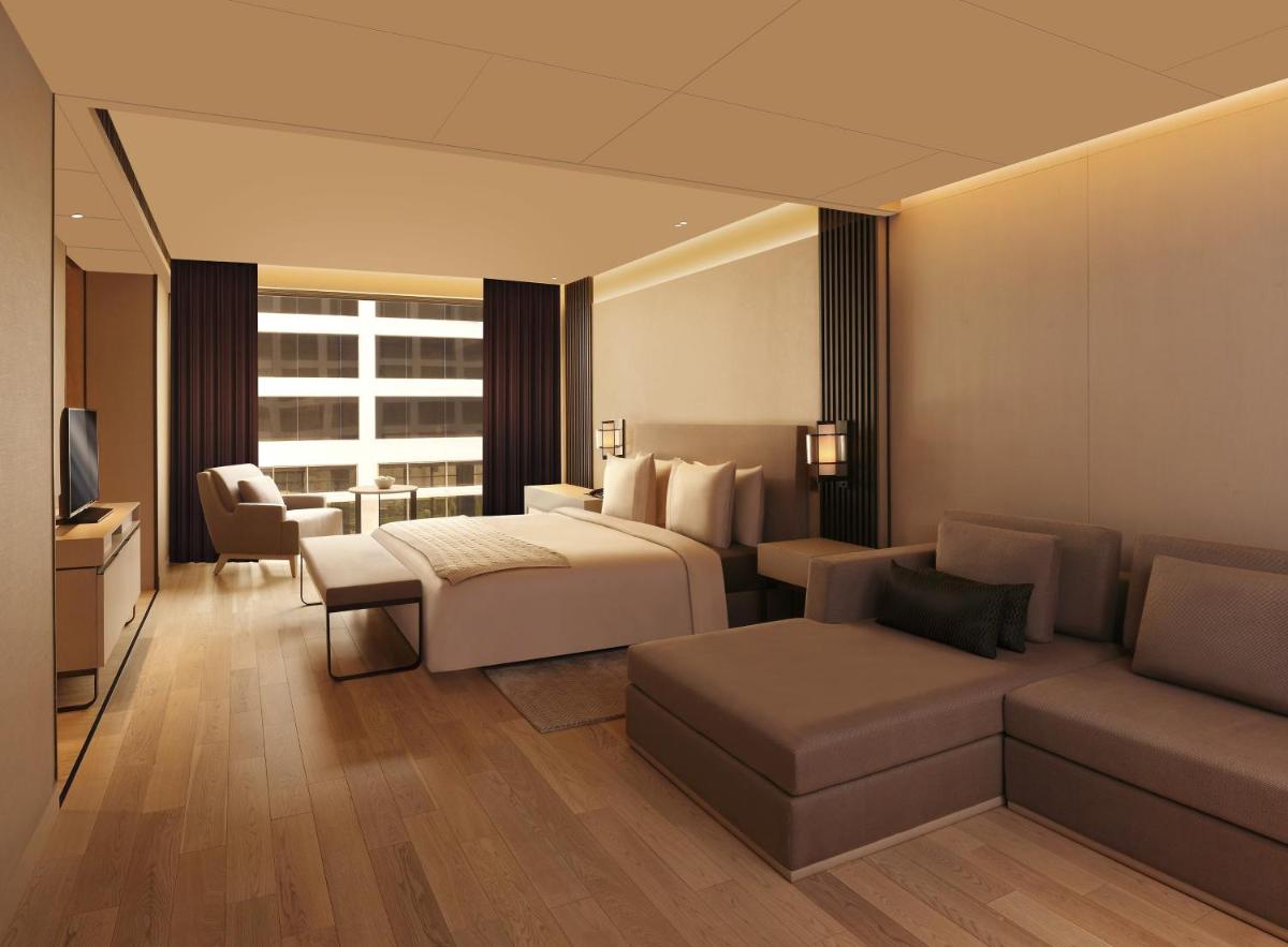 a hotel room with a bed and a couch at Roseate House New Delhi in New Delhi a hotel room with a bed and a couch at Roseate House New Delhi in New Delhi