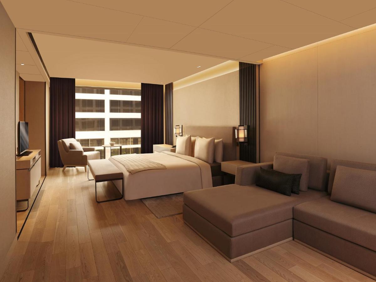 a hotel room with a bed and a couch at Roseate House New Delhi in New Delhi a hotel room with a bed and a couch at Roseate House New Delhi in New Delhi