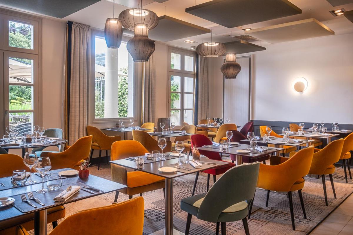 un restaurant avec des tables, des chaises et des fenêtres dans l'établissement Château Belmont Tours by The Crest Collection, à Tours