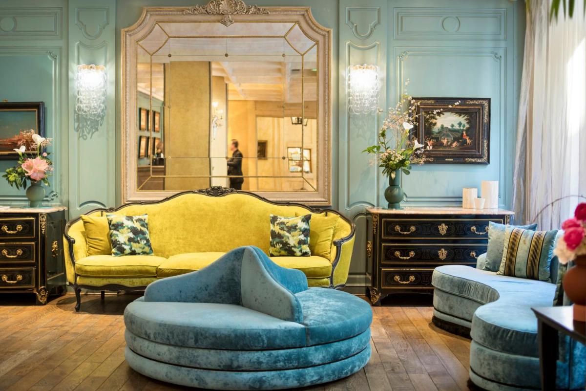 un salon avec un canapé jaune et un miroir dans l'établissement Castille Paris – Starhotels Collezione, à Paris