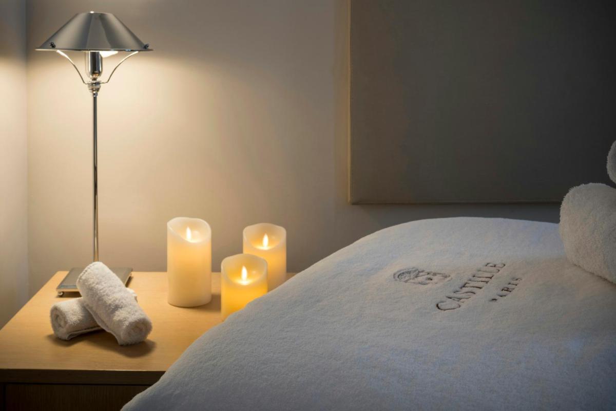 un lit avec deux bougies et deux serviettes sur une table dans l'établissement Castille Paris – Starhotels Collezione, à Paris