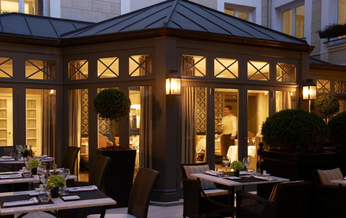 un restaurant avec des tables et des chaises devant un bâtiment dans l'établissement Castille Paris – Starhotels Collezione, à Paris