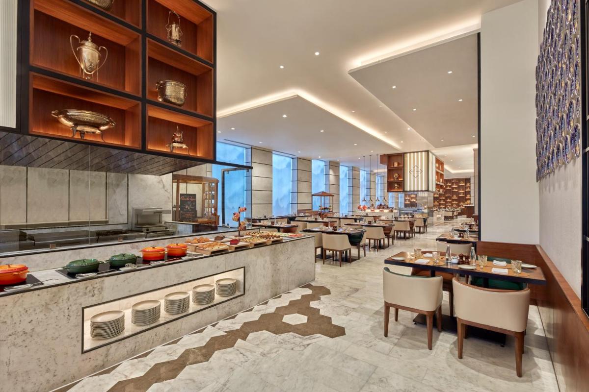 a restaurant with tables and chairs in a building at Novotel Jaipur Convention Centre in Jaipur