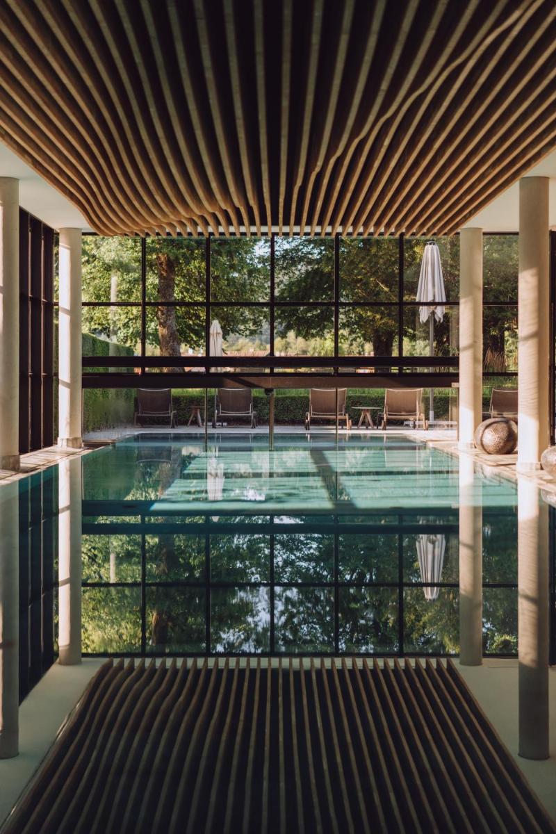 ein Swimmingpool in einem Haus mit einem großen Fenster in der Unterkunft Parkhotel Egerner Höfe in Rottach-Egern