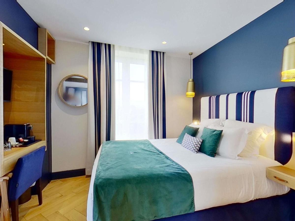 une chambre avec un grand lit et un mur bleu dans l'établissement MADISON Saint Jean de Luz - Handwritten Collection, à Saint-Jean-de-Luz