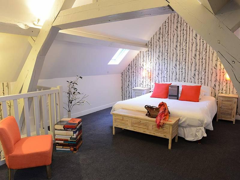 une chambre avec un lit aux oreillers rouges et une chaise dans l'établissement Domaine de Joinville & Spa, à Eu