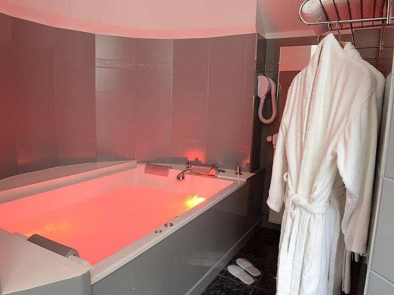 une salle de bain avec une baignoire et une lumière rouge dans l'établissement Domaine de Joinville & Spa, à Eu