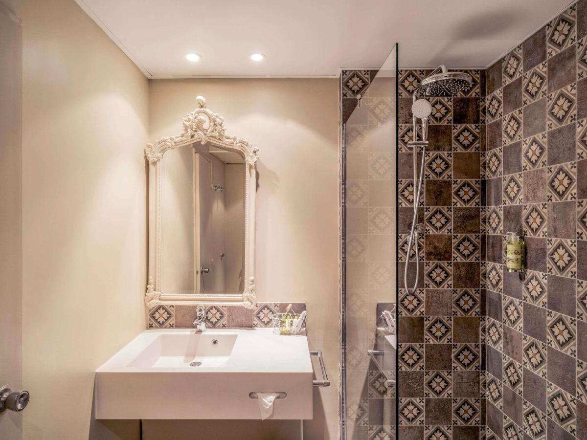 une salle de bains avec lavabo, miroir et douche dans l'établissement Hotel Mercure Parc du Coudray - Barbizon, à Le Coudray-Montceaux