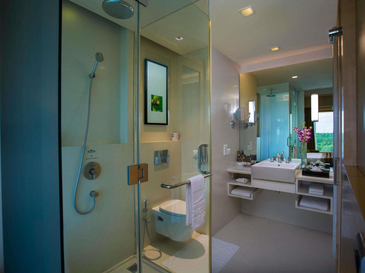 a bathroom with a shower and a toilet and a sink at Novotel Hyderabad Airport in Hyderabad