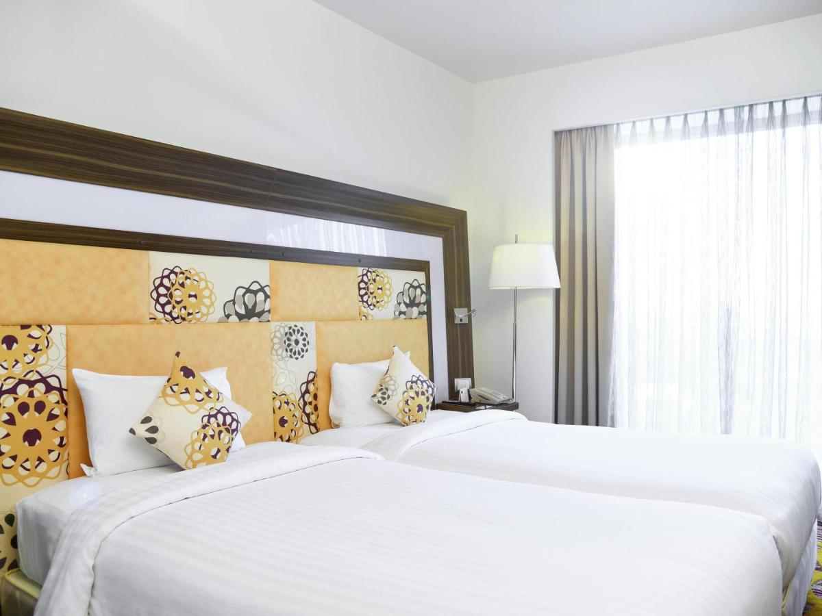 a bedroom with two large white beds and a window at Novotel Pune Viman Nagar Road in Pune
