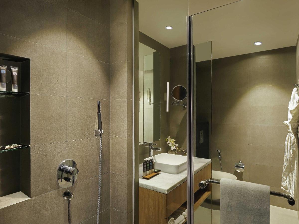 a bathroom with a sink and a glass shower at Novotel Mumbai Juhu Beach in Mumbai